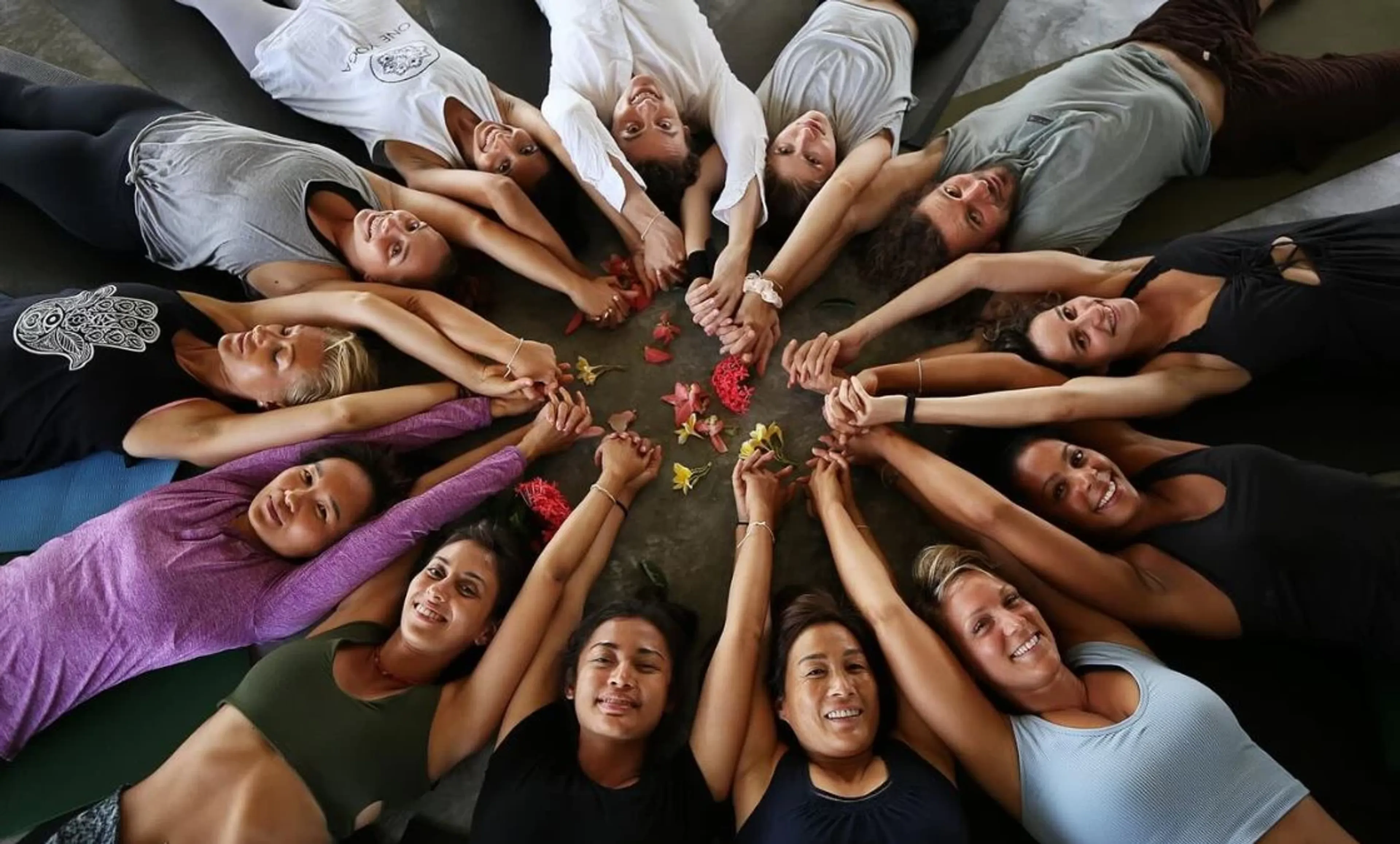 Gruppe von Frauen im Kreis mit haltenden Händen bei einem Yoga Retreat