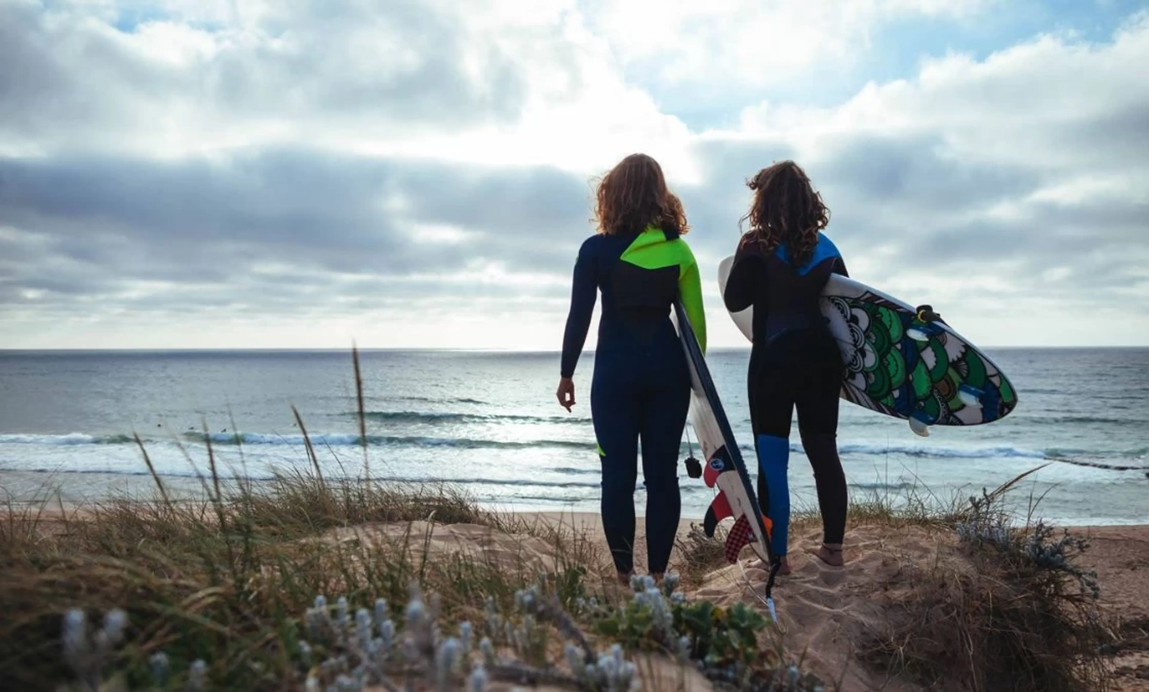 Zwei Surfer in Portugal beobachten die Wellen von der Klippe
