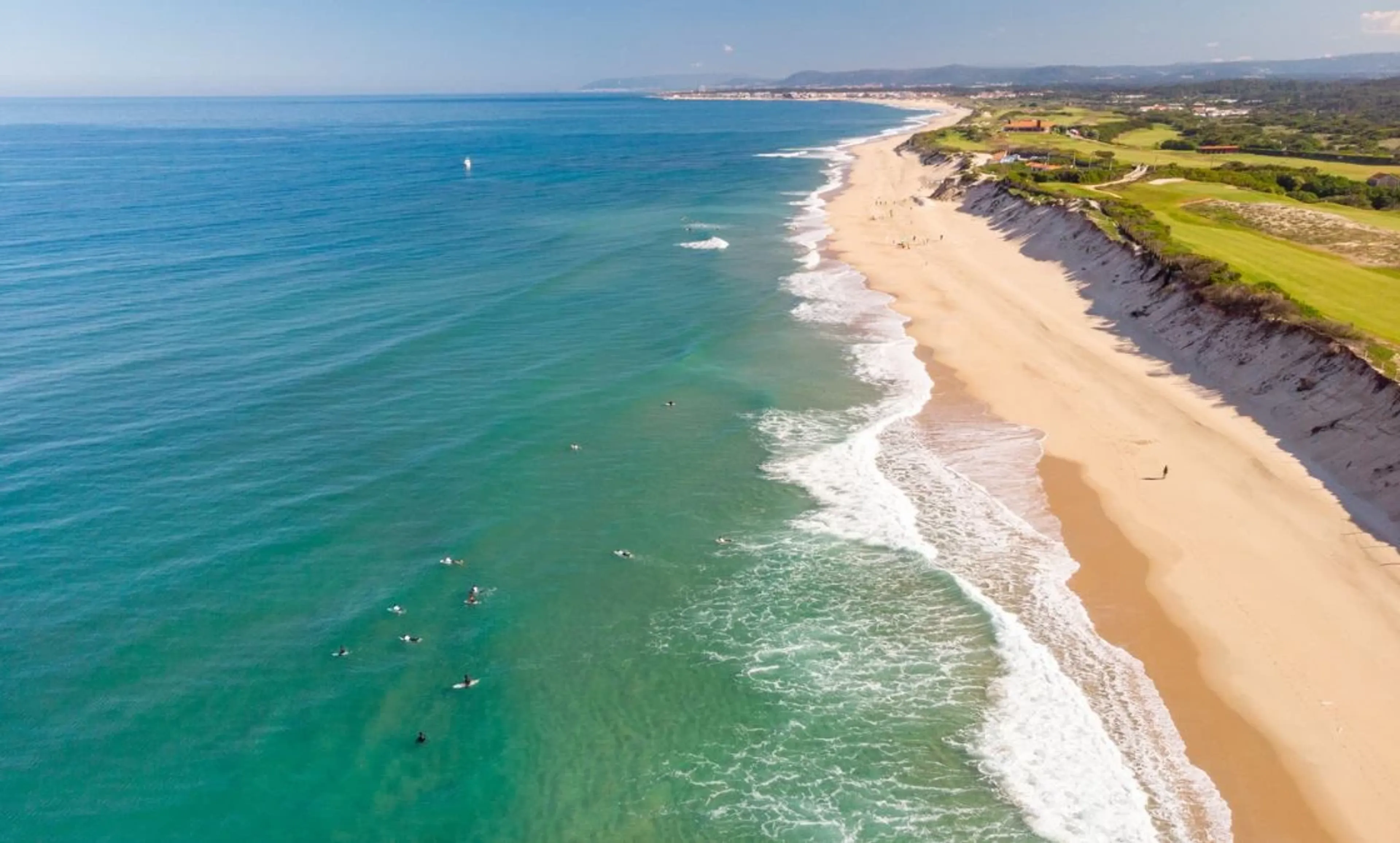 Blick über endlosen Sandstrand mit Surfern in Nordportugal