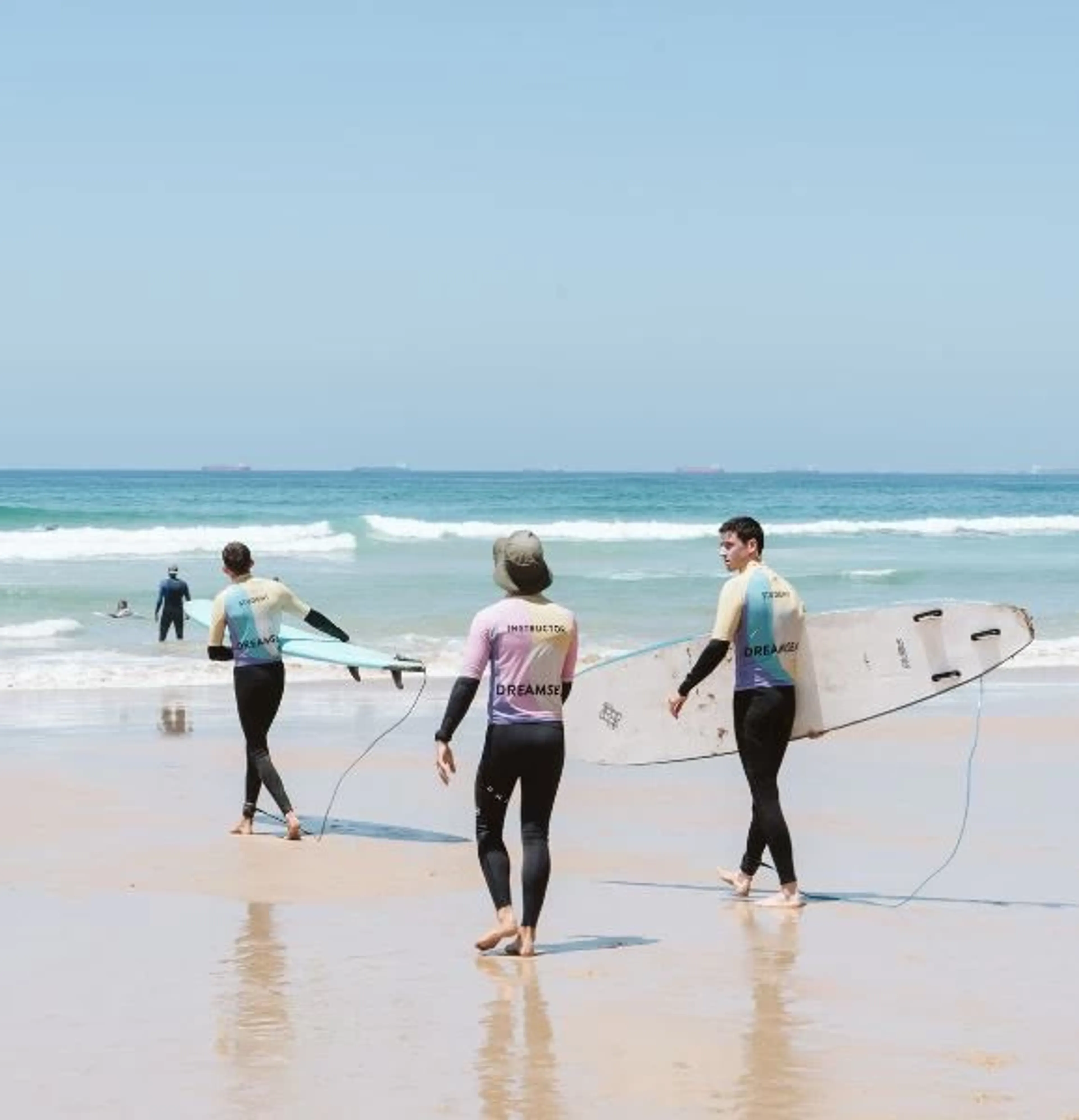 Surfcamp-Gruppe mit Surflehrer auf dem Weg in die Wellen