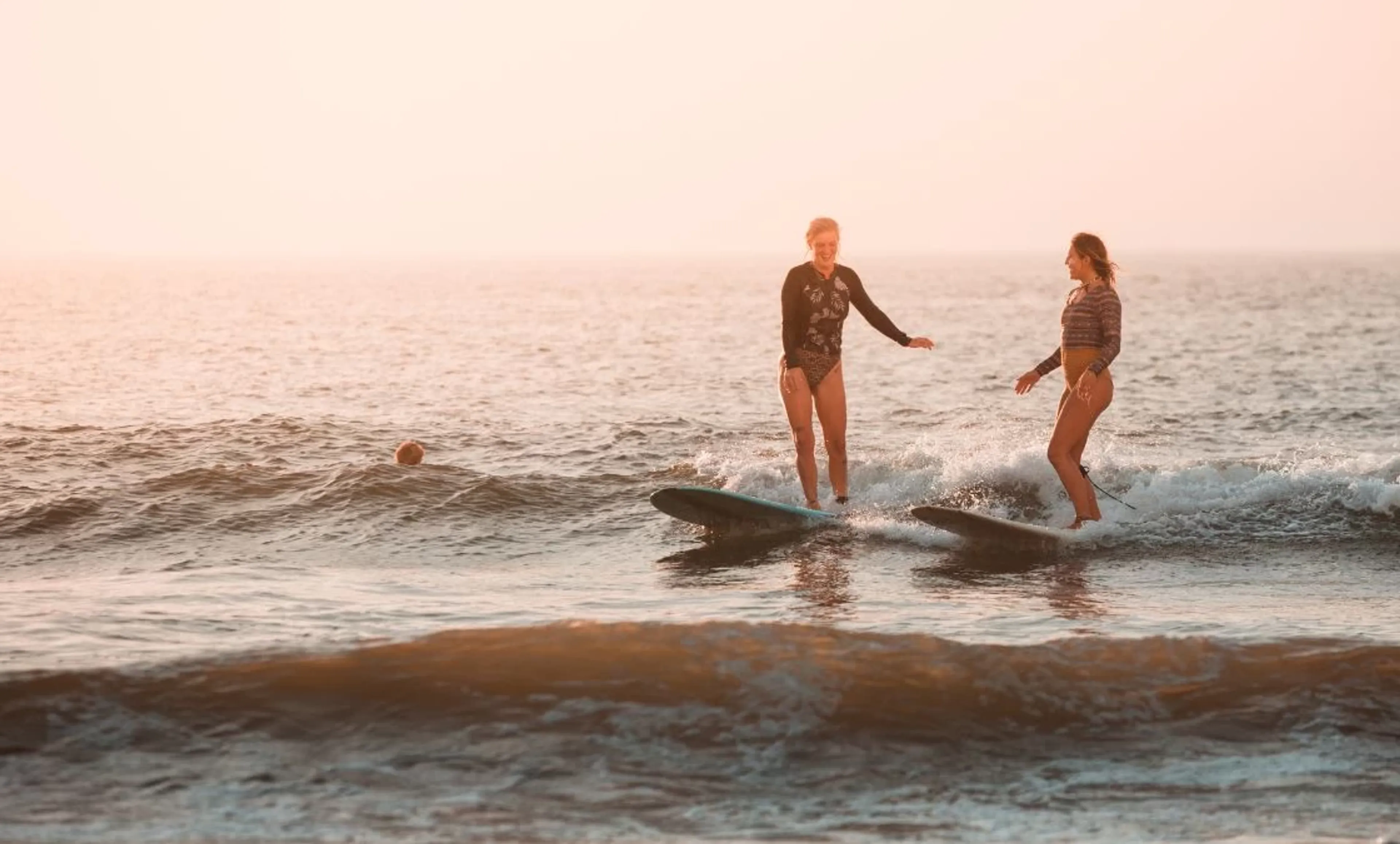 Zwei Frauen im Surfcamp surfen ihre erste Welle zusammen