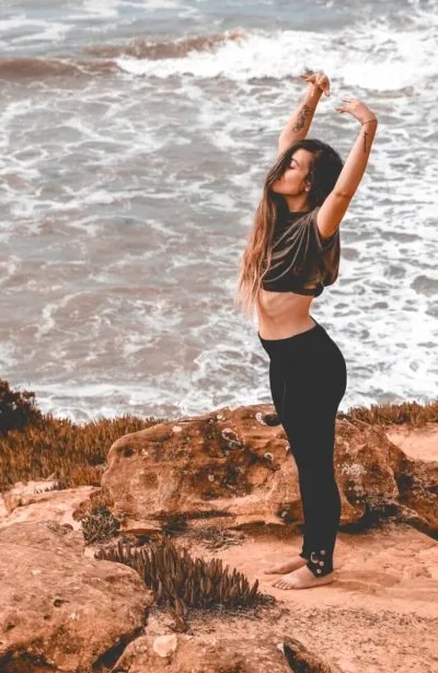 Frau in Yoga Pose am Meer in Portugal