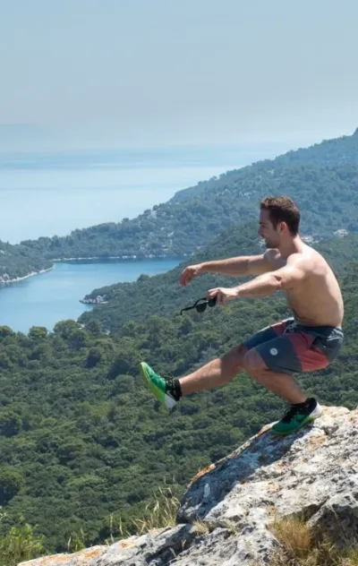 Mann in Fitness-Pose mit der Küstenlandschaft Kroatiens im Hintergrund