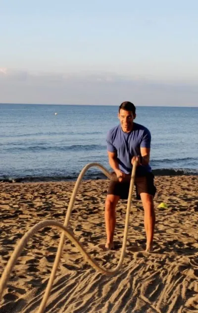 Mann trainiert mit Seil am Strand auf Mallorca