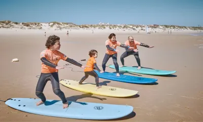 Familie lernt beim Surfkurs am Strand den Take-off