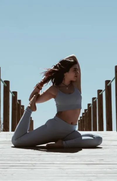 Frau beim Yoga auf einem Steg in Richtung Meer