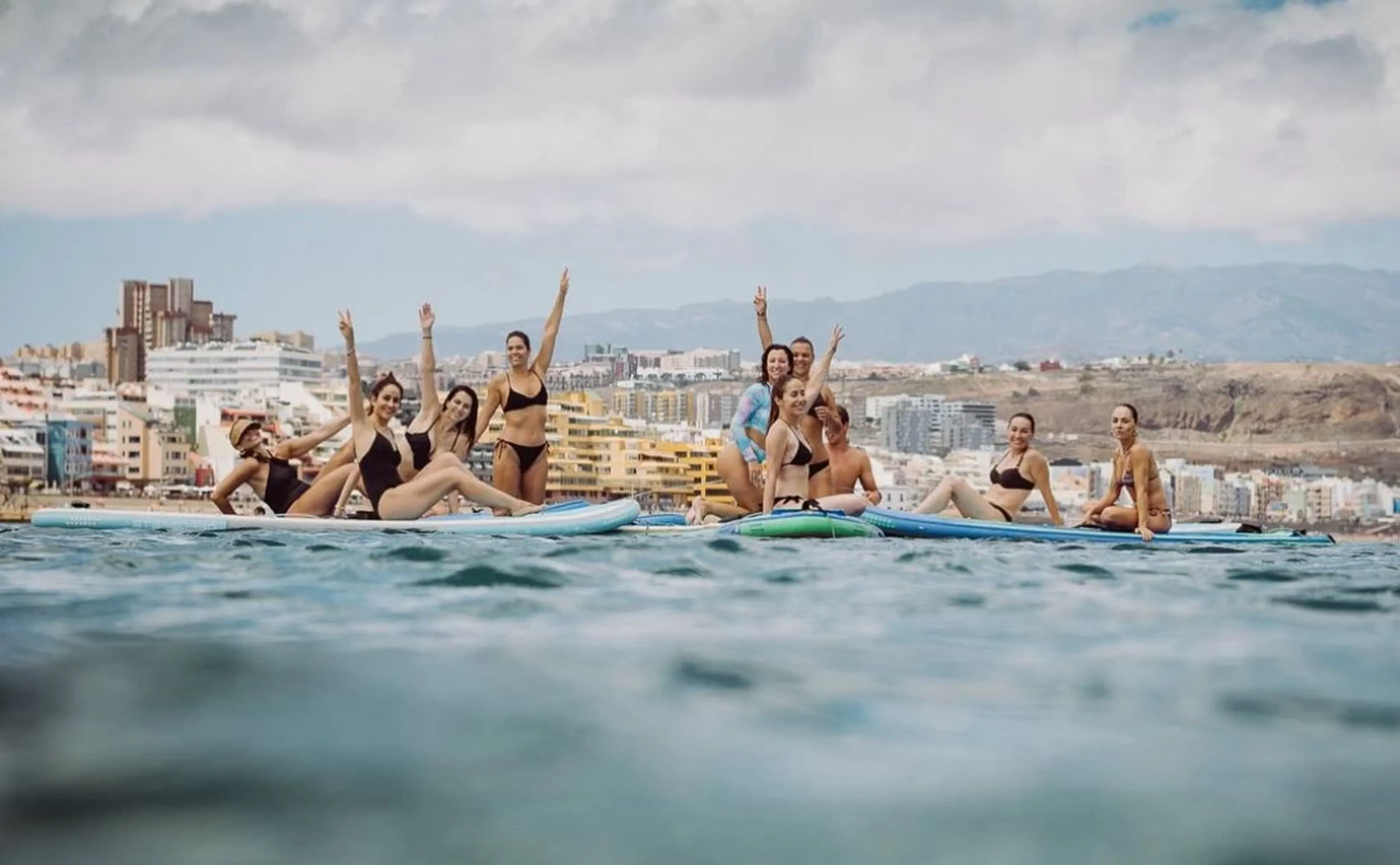 Gruppe jubelt auf ihren Surfboards im Wasser auf Gran Canaria