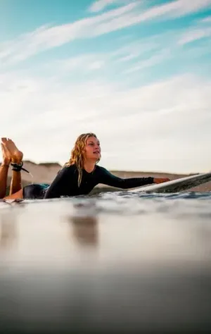 Frau paddelt auf dem Surfboard raus in die Wellen in Südwestfrankreich