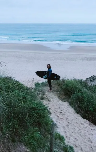 Mann auf den Klippen mit Surfboard und Blick auf die Wellen in Nordspanien