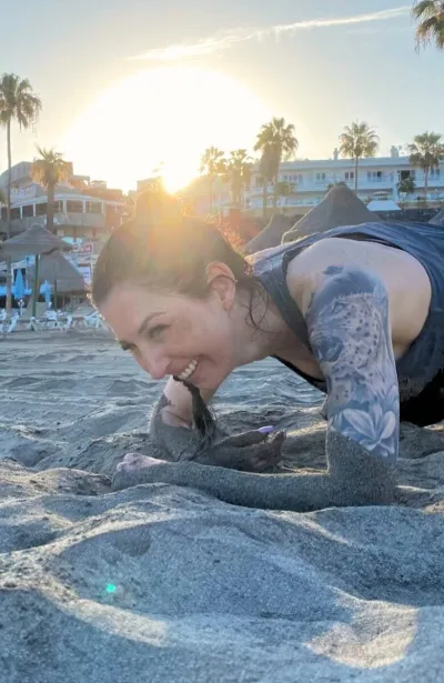 Frau lacht beim anstrengenden Fitnesstraining am Strand