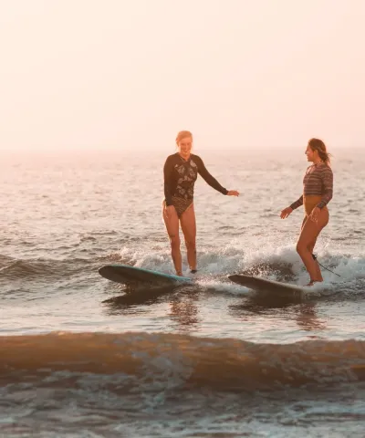 Zwei Freundinnen surfen gemeinsam eine Welle im Surfcamp in Frankreich