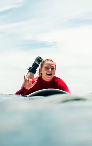 Frau strahlt auf ihrem Surfboard nach einer gesurften Welle auf Bali