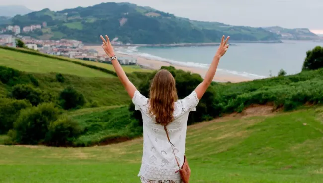 Frau mit Blick auf das Meer und hoch gestreckten Armen