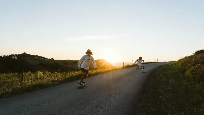 Drei Gäste aus dem Surfcamp in Nordspanien surfskaten bei Sonnenuntergang