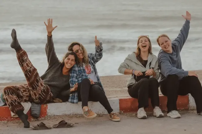 Eine Gruppe Frauen sitzt lachend am Strand