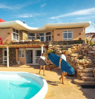 Paar mit Surfboards vor Luxus Surfhaus auf Fuerteventura