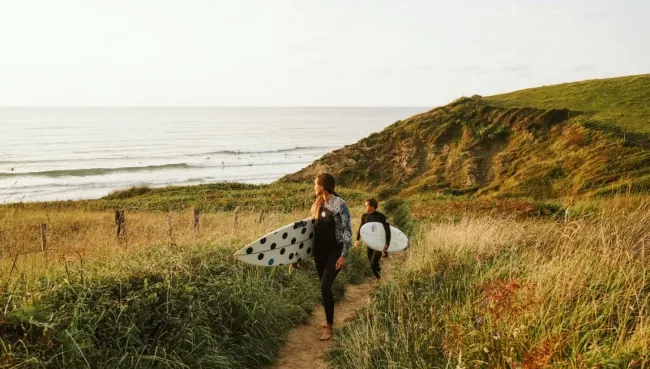 Zwei Surfer nach der Surf-Session mit Blick auf die Wellen in Kantabrien