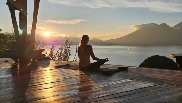 Frau meditiert am See bei Sonnenuntergang