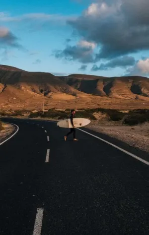 Mann läuft mit seinem Surfboard zum Strand auf Lanzarote