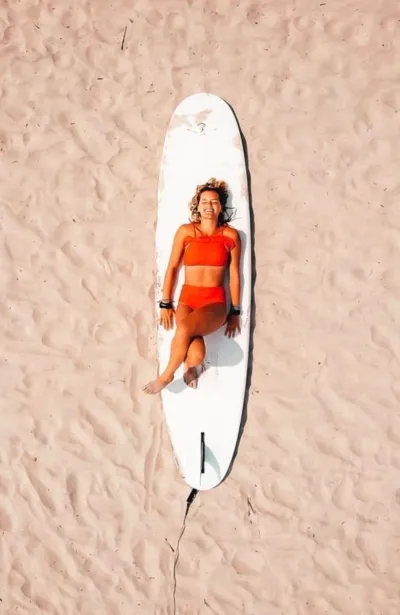 Frau liegt auf SUP Board am Strand im Yoga Retreat