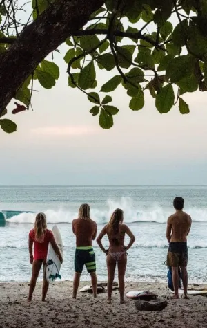 Gruppe von Surfern am Strand mit Blick auf die Wellen in Santa Teresa