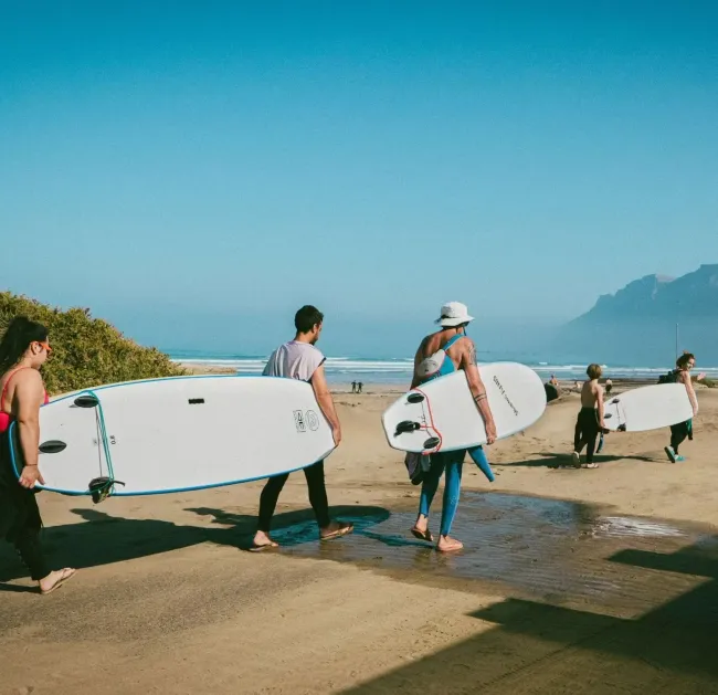 Gruppe läuft zum Surfkurs am Strand auf Lanzarote
