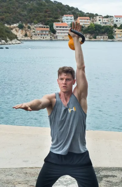 Mann trainiert mit Kettlebell am Meer in Kroatien