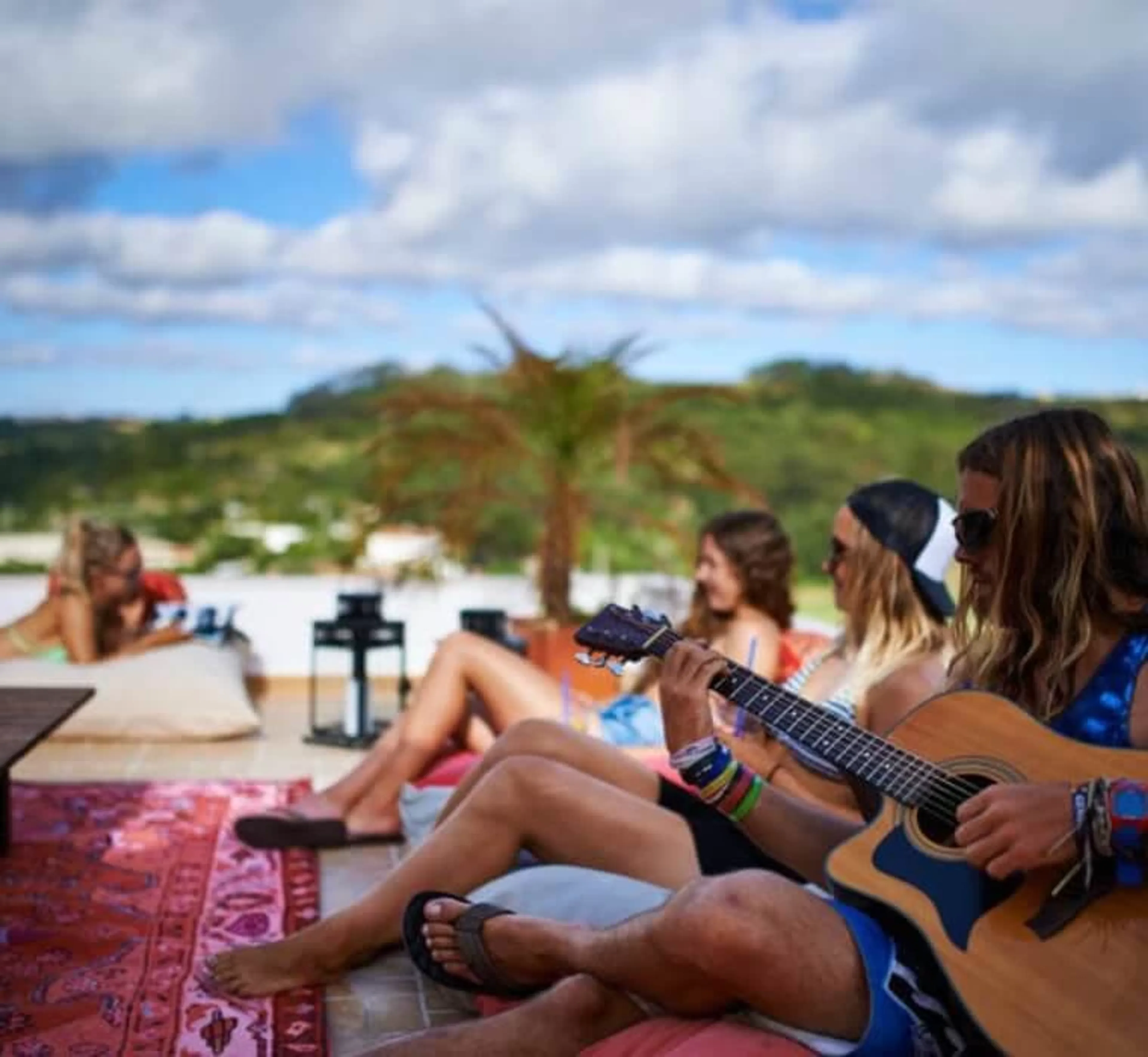 Surfcamp Gruppe sitzt mit Gitarre auf der Dachterrasse im Surfhaus in Ericeira zusammen