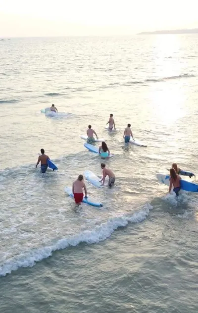 Surfcamp Gruppe läuft am Strand in Weligama mit ihren Surfboards ins Wasser