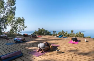 Gruppe beim Yoga auf einer Plattform mit Blick auf das Meer in Spanien
