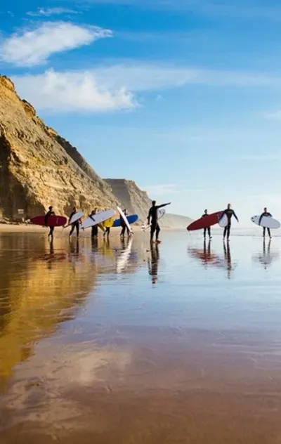 Surfcamp-Gruppe auf dem Weg in die Wellen am Strand in Ericeira