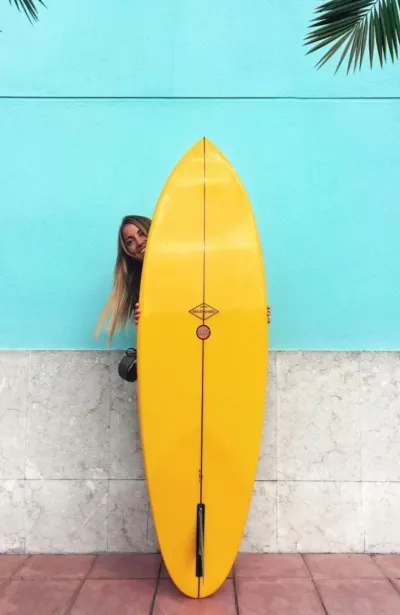 Frau lächelt hinter dem Surfboard im Surfhaus in Nordspanien