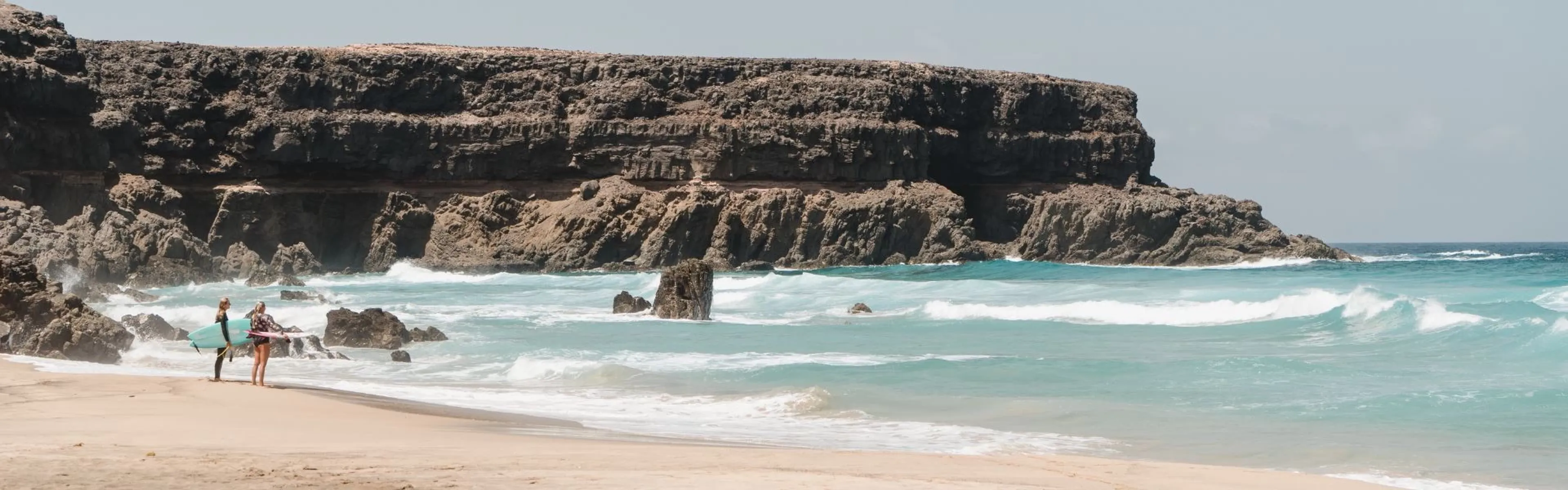 Zwei Surfer am Strand auf Fuerteventura mit Blick auf die Wellen