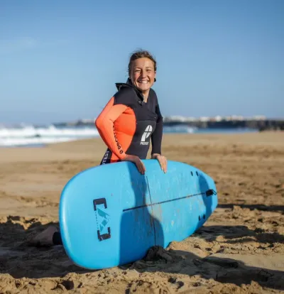 Frau mit Surfboard am Strand auf Fuerteventura