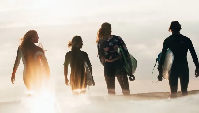 Gruppe mit Surfboards läuft bei Sonnenaufgang zum Strand