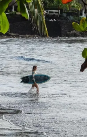 Frau läuft mit ihrem Surfboard in die Wellen in Costa Rica