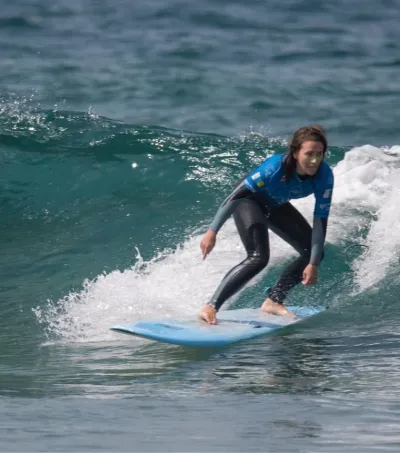 Fortgeschrittene Surfschülerin surft eine grüne Welle auf Gran Canaria