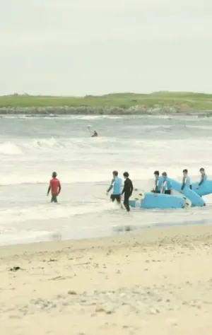 Surfcamp Gruppe auf dem Weg in die Wellen mit ihrem Surflehrer in Irland