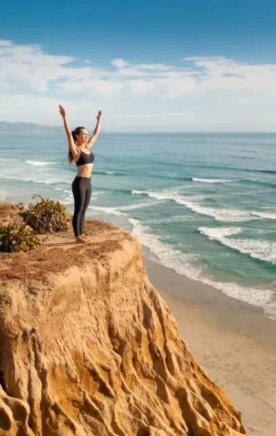 Frau mit hochgestreckten Armen und Blick auf das Meer auf Kreta