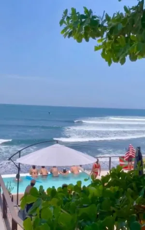 Gruppe blickt vom Infinity Pool auf die Wellen im Surfcamp in El Salvador