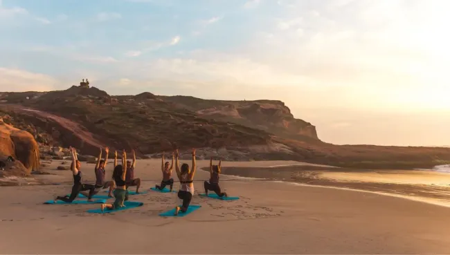Gruppe beim Yoga am Strand in Portugal
