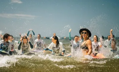 Schulklasse im Wasser beim Surfunterricht am jubeln