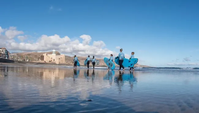 Surfcamp-Gruppe läuft mit Surfboards am Strand auf Gran Canaria
