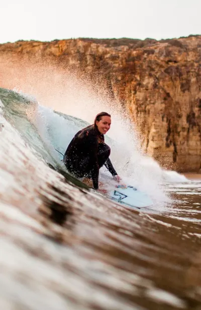 Frau surft Welle in Portugal