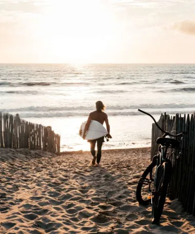 Surfer läuft mit Surfboard zum Strand in Gironde