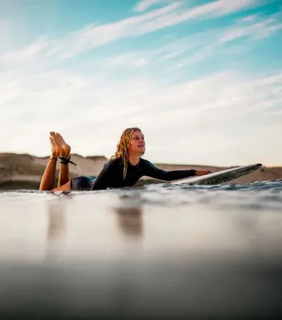 Surf-Anfängerin paddelt mit ihrem Surfboard raus in die Wellen in Frankreich