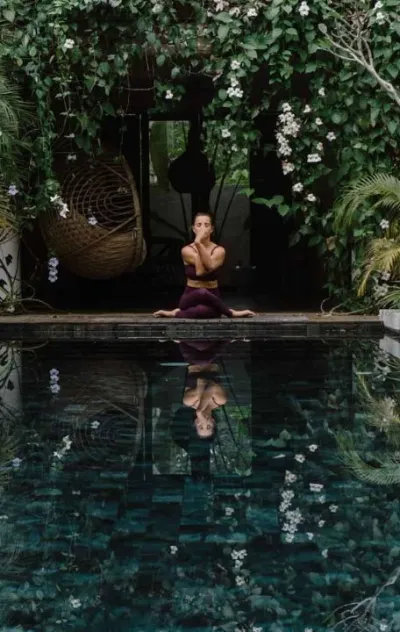 Frau beim Yoga am Pool auf Bali