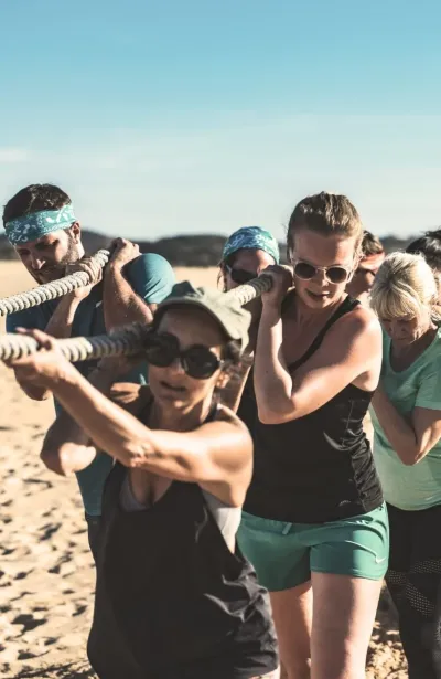 Fitnessgruppe beim Tauziehen am Strand