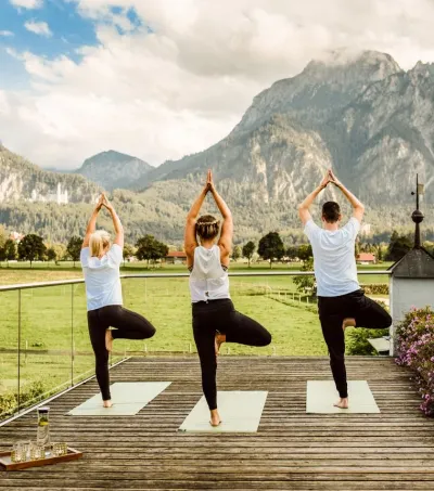 Gruppe in der Tree Pose beim Yoga mit Blick auf die Berge