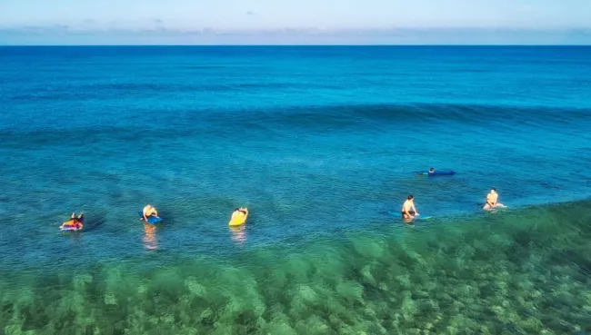 Surfcamp Gruppe im Wasser mit Blick auf die nächste Welle
